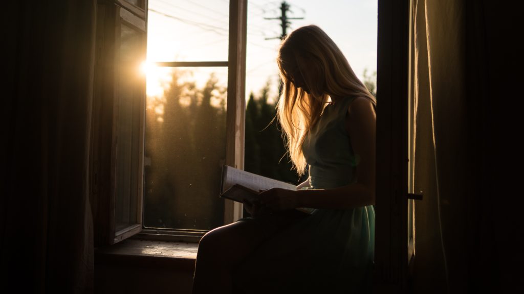 Girl reading in window at sunset